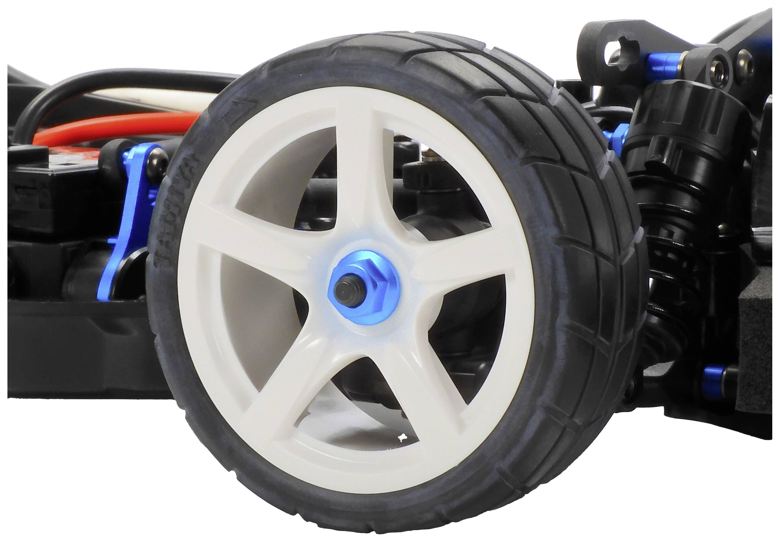 Nahaufnahme eines Modellautorreifens mit schwarzer Gummibereifung und weißer Felge auf einem mechanischen Unterbau.