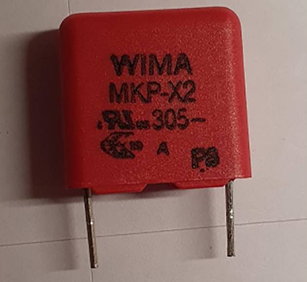 Roter WIMA MKP-X2 Kondensator mit zwei Metallpins, auf einer weißen Oberfläche liegend, zeigt technische Informationen auf seiner Vorderseite.