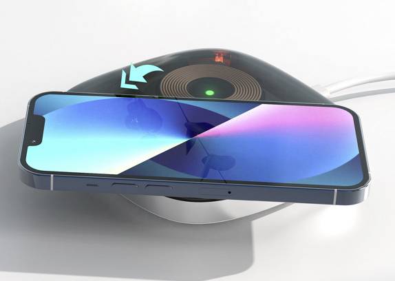 Ein Smartphone liegt auf einem kabellosen Ladegerät. Ein grünes Licht deutet darauf hin, dass das Gerät geladen wird.