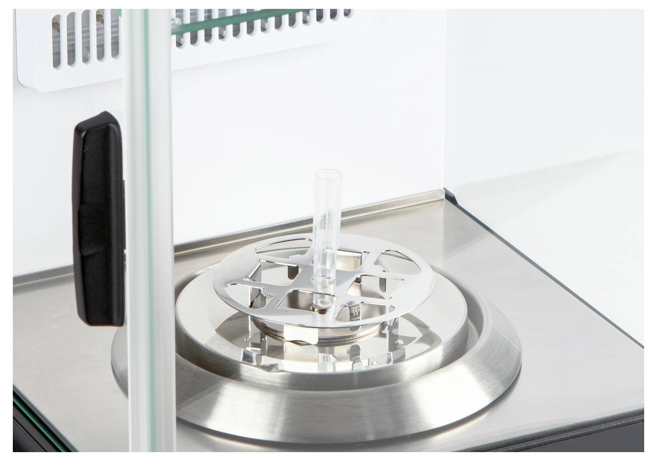 Eine Laborapparatur mit einer runden Metallbasis und einem zylindrischen Glasaufsatz, in einem sterilen Bereich platziert.