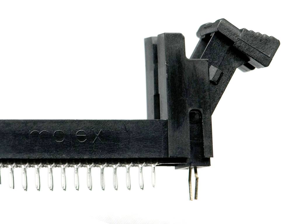 Ein schwarzer elektrischer Steckverbinder mit vielen Metallstiften, die aus der unteren Seite herausragen, auf weißem Hintergrund.