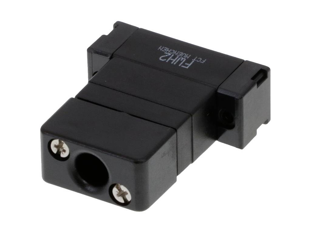 Ein rechteckiger schwarzer Adapter mit zwei sichtbaren Schraubköpfen und einer zentralen Öffnung, liegt auf einer weißen Oberfläche.