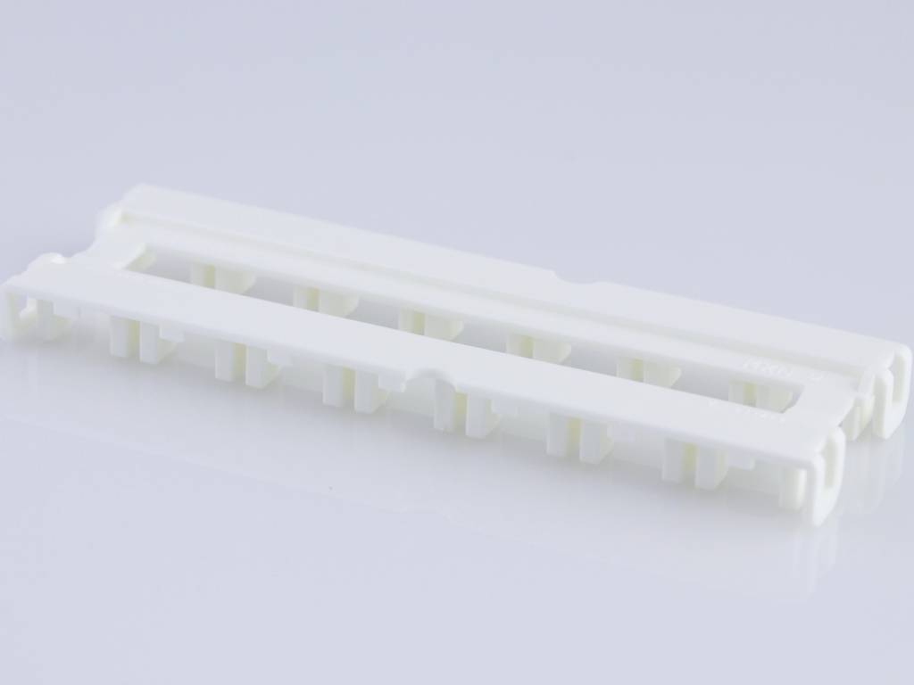 Plastikzahnleiste mit mehreren parallelen Schlitzen, verwendet als Werkzeug für die Sicherung von Objekten oder Kabeln.