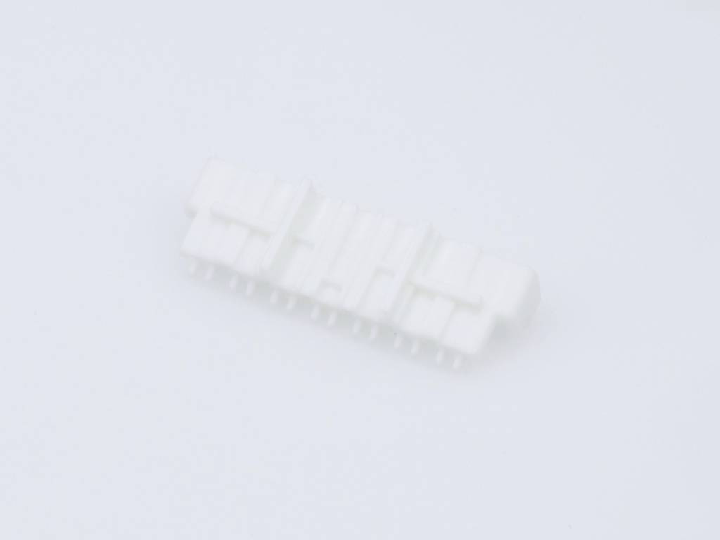 Ein weißer Kunststoffstecker mit mehreren Anschlussstiften liegt auf einer weißen Oberfläche.