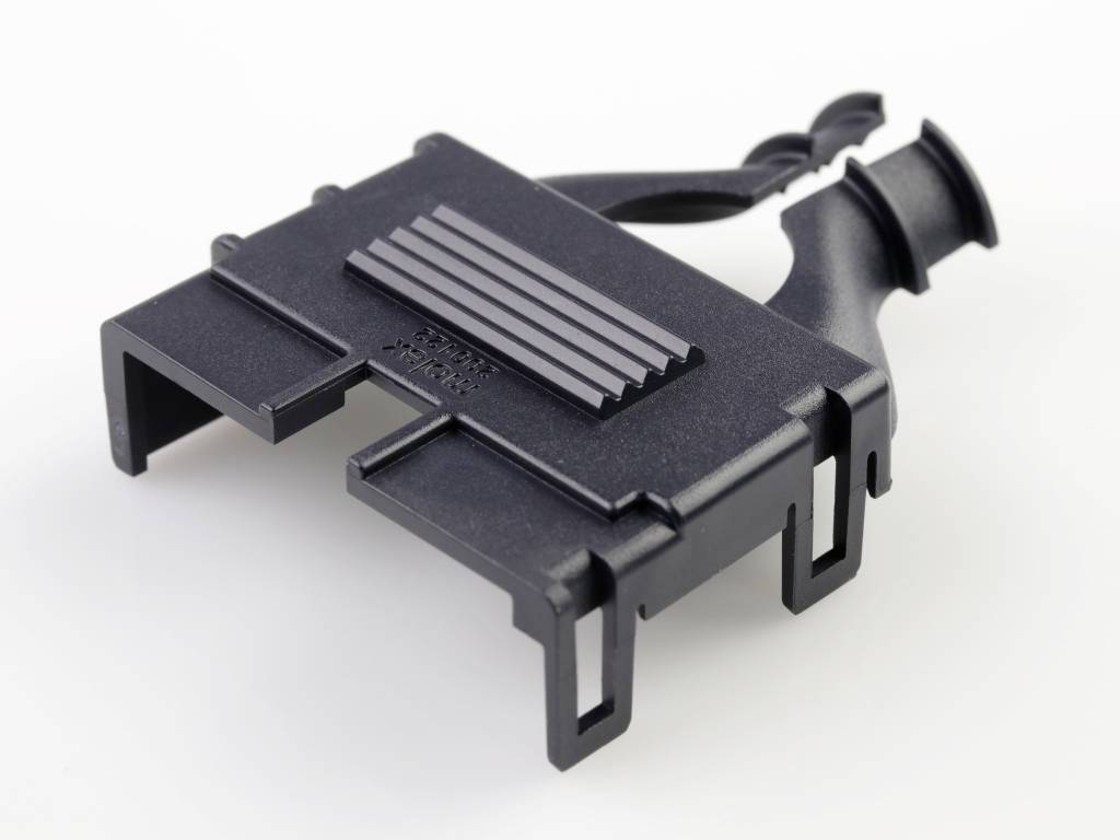 Schwarzes Plastikteil mit rechteckiger Form und geriffelten Linien, vermutlich ein technisches Bauteil oder Clip, auf weißem Hintergrund.