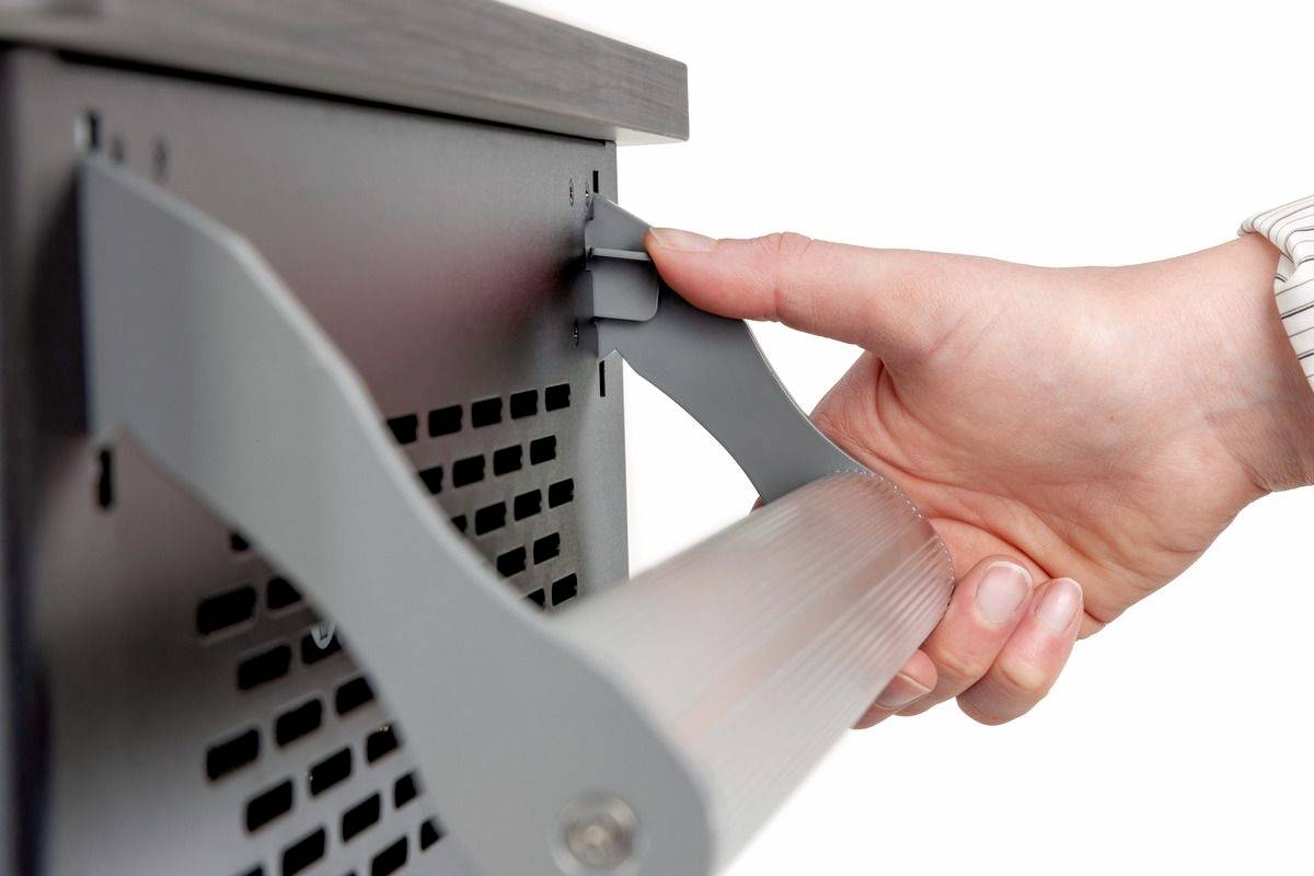 Hand zieht an einem grauen Hebel eines elektronischen Geräts. Es scheint, als ob eine Abdeckung oder Klappe geöffnet wird.
