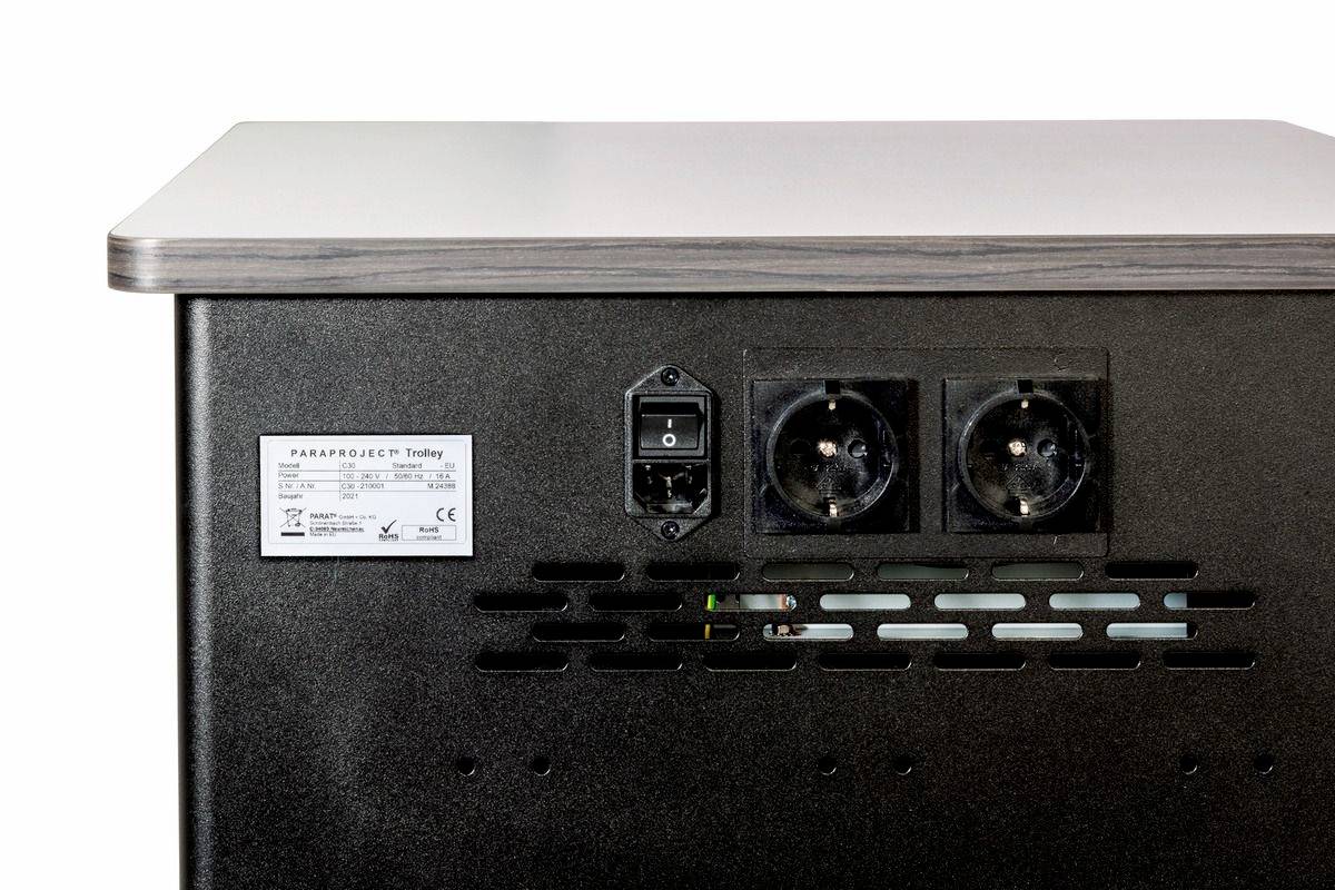 Rückansicht eines schwarzen Geräts mit zwei Steckdosen, einem Netzschalter und einem Etikett mit technischen Daten.