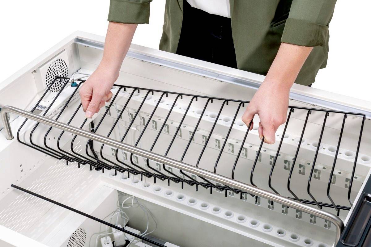 Person hält ein Gestell in einem Geschirrspüler. Geschirrspüler ist leer und offen, Hände richten Gestell aus.