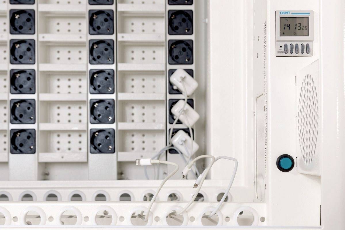 Weiße Schaltzentrale mit mehreren Steckdosen und einem digitalen Timer, zeigt 14:13 Uhr an. Kabel sind teilweise eingesteckt.
