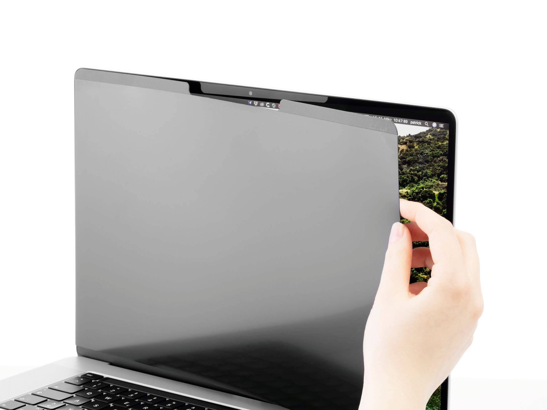 Eine Hand hält einen Blickschutzfilter, der auf einen Laptopbildschirm aufgesetzt wird, um Inhalte vor unerwünschtem Einsehen zu schützen.