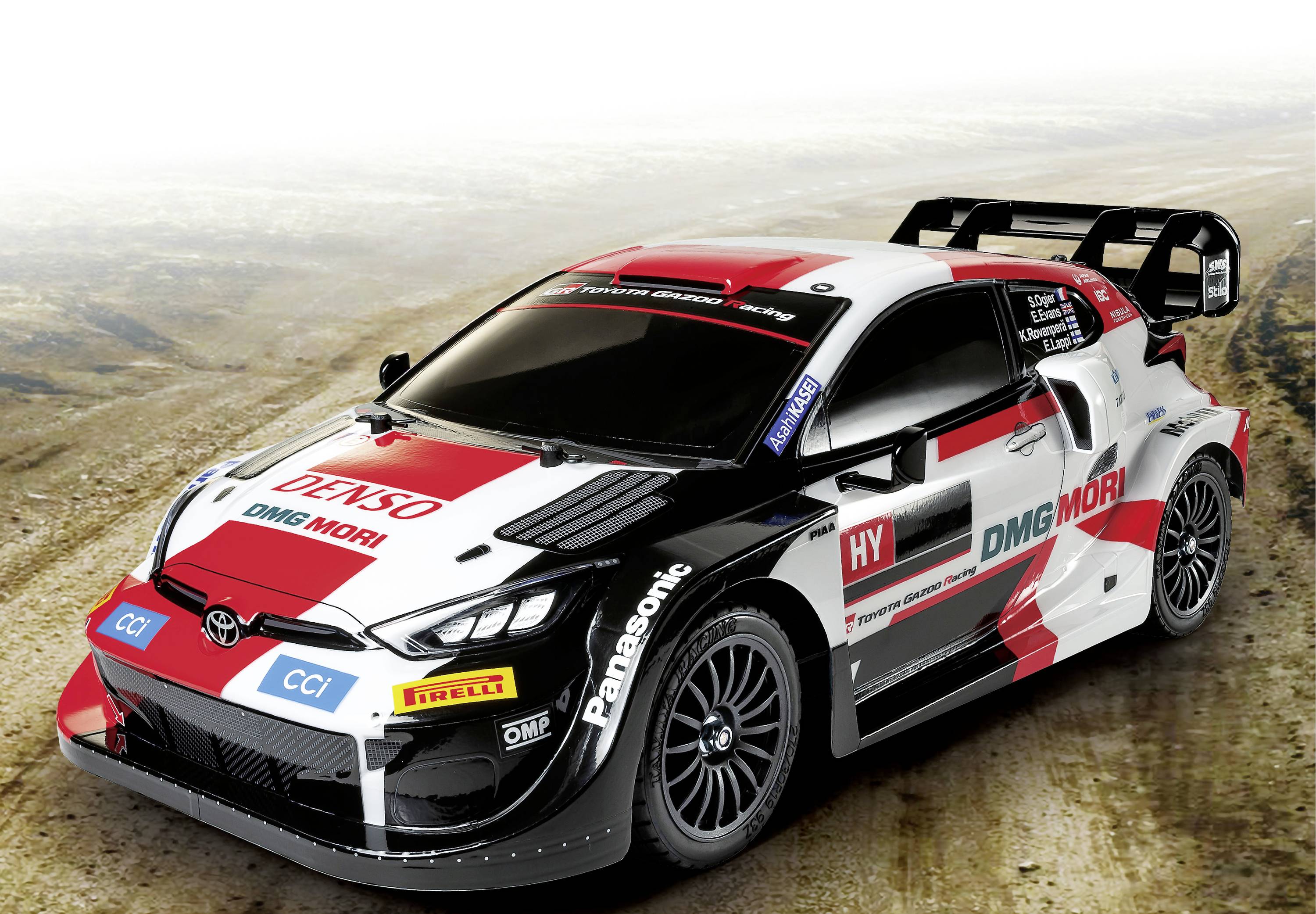 Rallyeauto mit mehrfarbiger Lackierung und Sponsorenlogos steht auf einer staubigen Fläche. Es sieht schnell und sportlich aus.