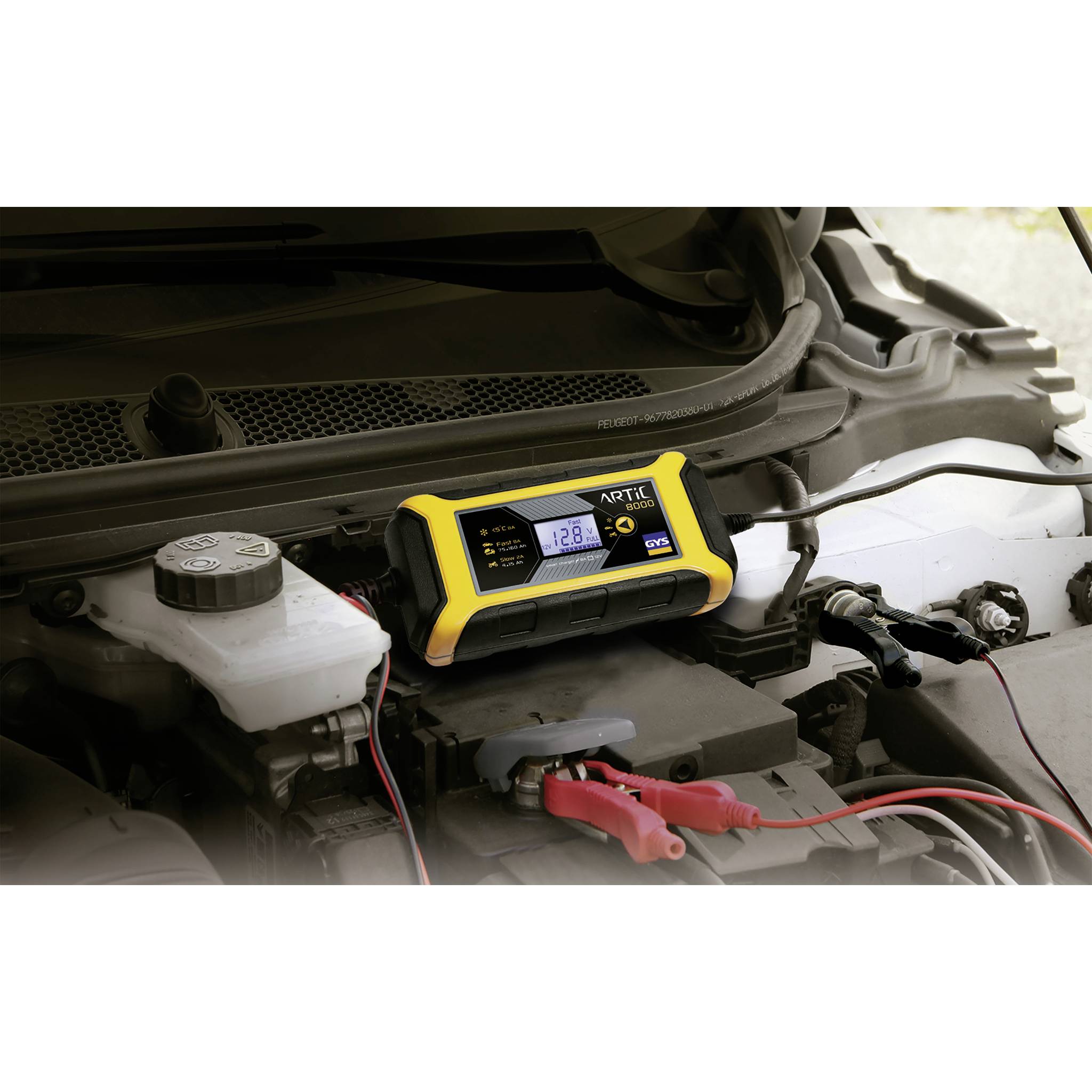 Ein gelbes Batterieladegerät zeigt eine Spannung von 12,8 Volt auf dem Bildschirm an. Es ist an eine Autobatterie angeschlossen.