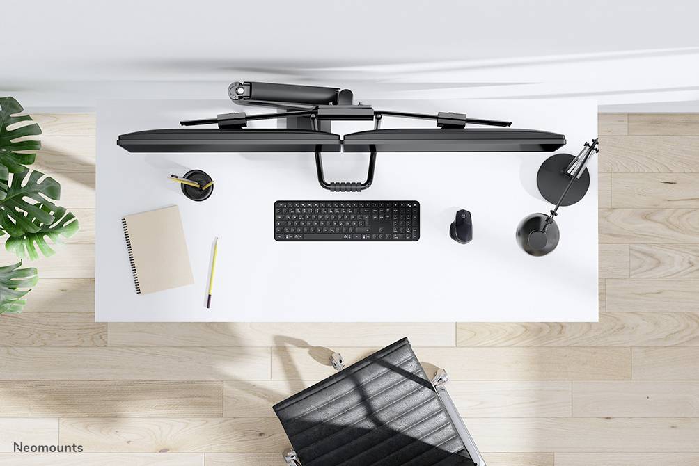 Ein moderner Arbeitsplatz von oben: weißer Tisch mit Tastatur, Maus, Notizbuch, Stift, Monitorhalterung und Schreibtischlampe.