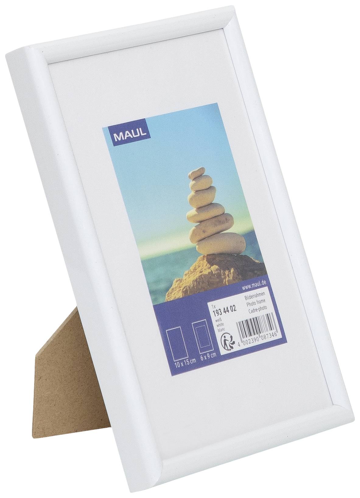 Ein weißer Bilderrahmen mit einem Foto von gestapelten Steinen auf einem Felsen am Meer. Im Hintergrund blauer Himmel und Wasser.