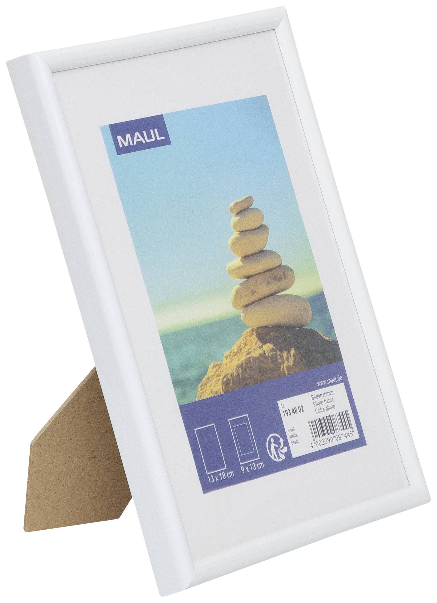 Ein weißer Bilderrahmen mit einem Foto von gestapelten Steinen vor einem blauen Himmel und Meereshintergrund. Packaging zeigt Größe 13x18 cm.