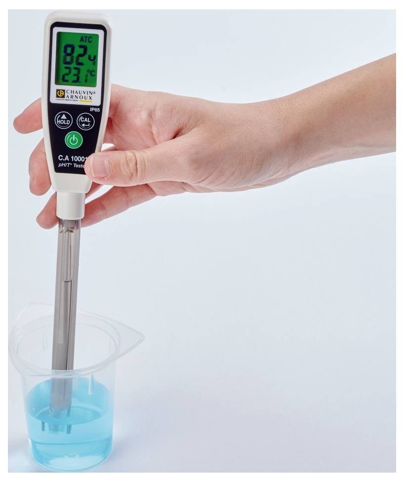 Eine Hand hält ein digitales pH-Messgerät, das in einem Becher mit blauer Flüssigkeit steckt. Display zeigt pH 8,24 und Temperatur 23,7°C.