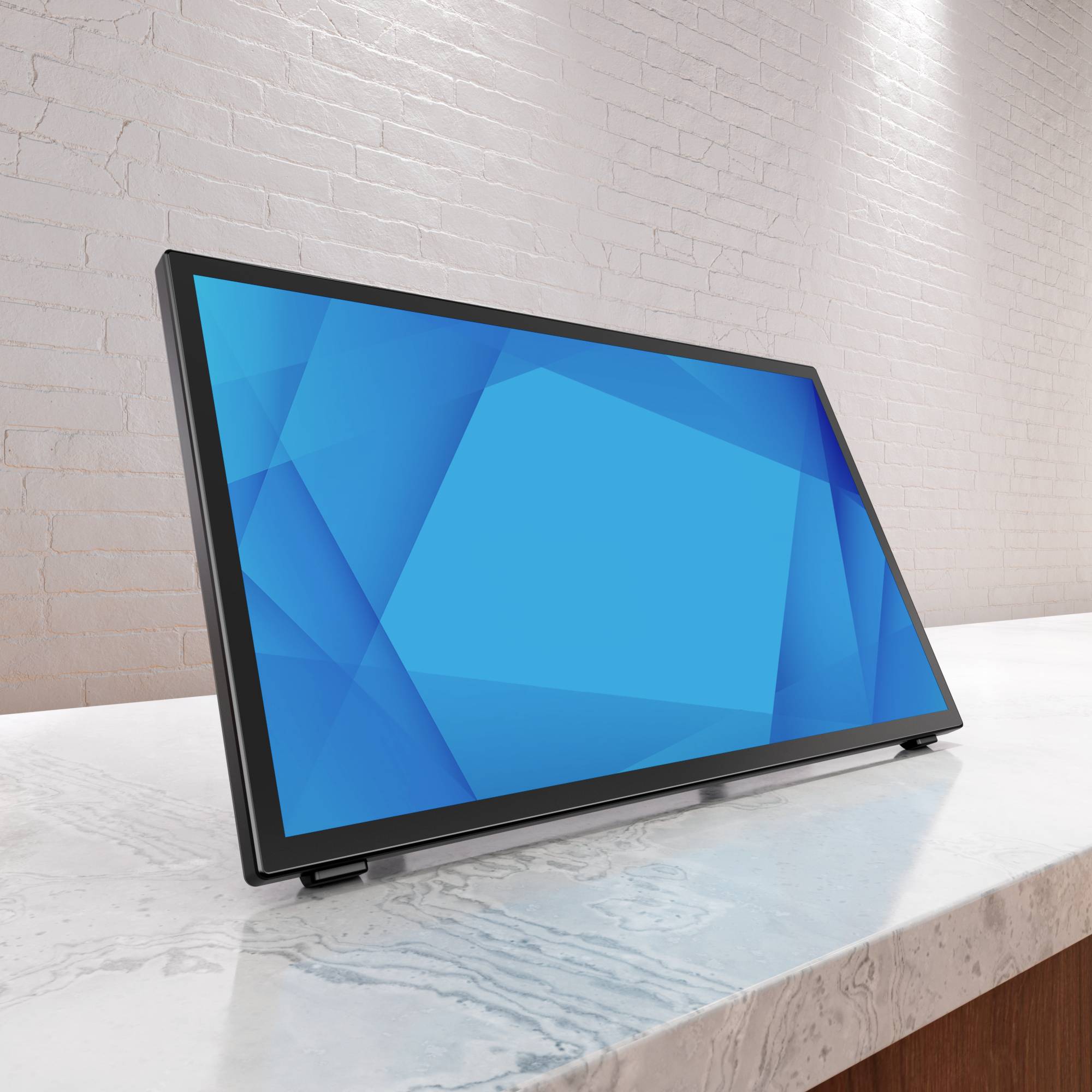 Ein moderner, flacher Computermonitor steht auf einem Marmortisch vor einer hellen Ziegelwand. Der Bildschirm zeigt ein blaues, geometrisches Muster.