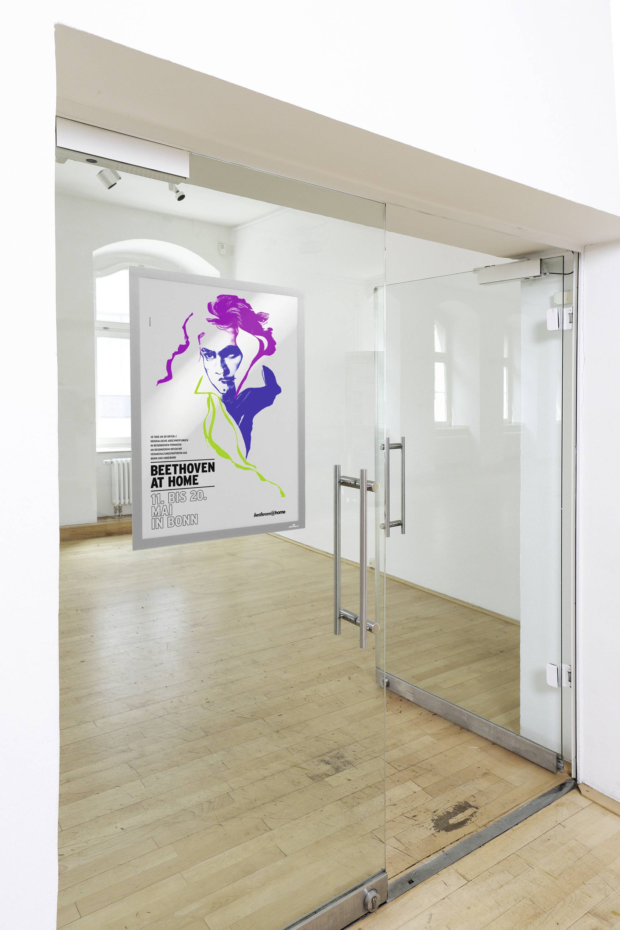 Ein Poster an einer Glastür zeigt ein buntes Porträt mit dem Titel 'Beethoven at Home', präsentiert von Los Baristas in einer Galerie.