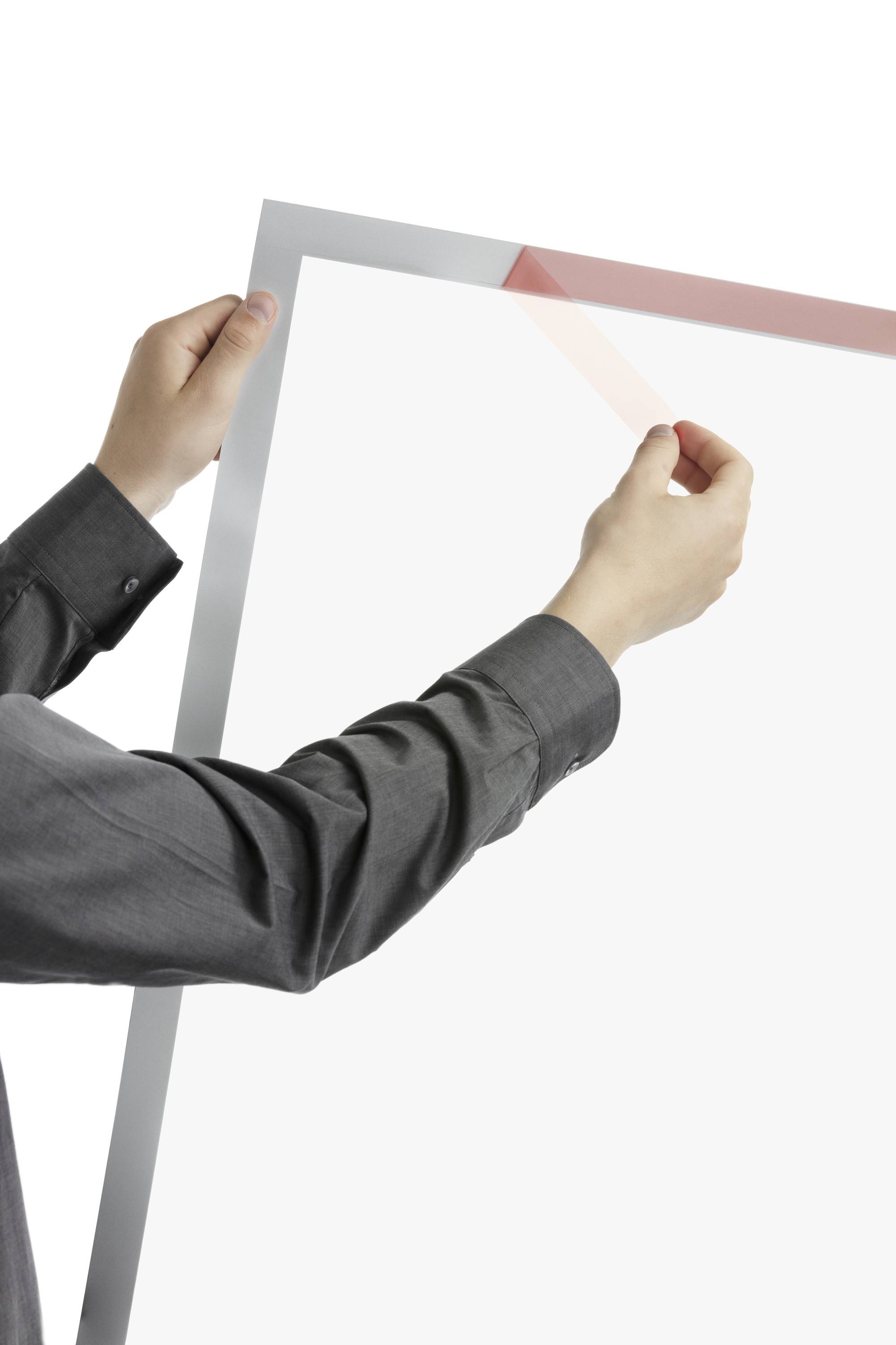 Eine Person in einem grauen Hemd hält einen großen Rahmen aus transparentem Material. Der Rahmen ist leicht umrandet.