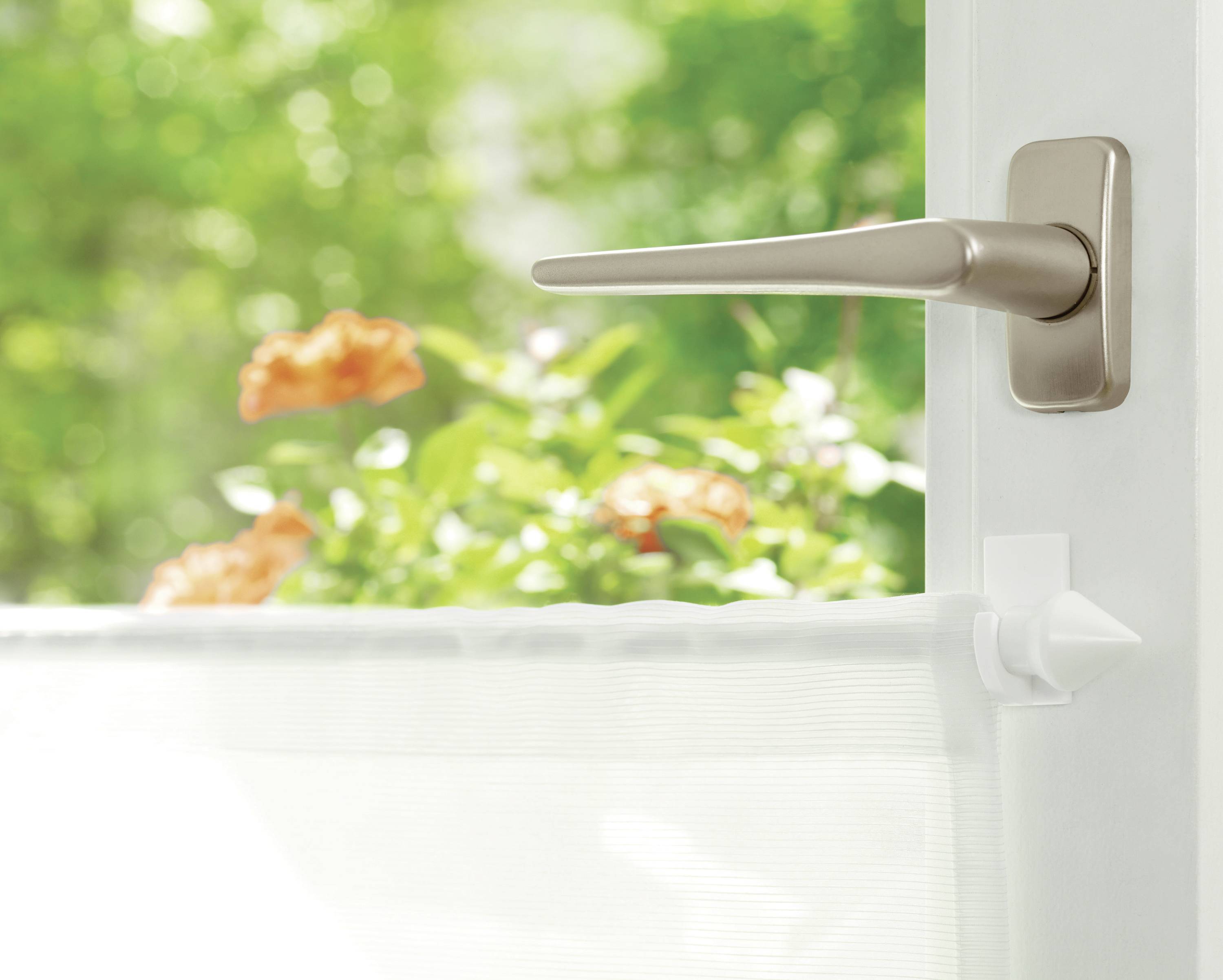 Eine offene Tür zeigt einen sonnigen Garten mit blühenden Pflanzen draußen.