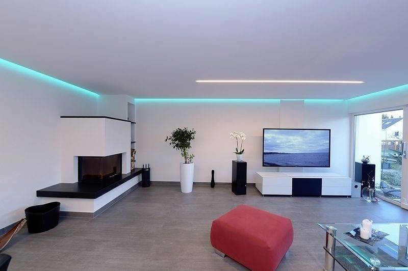 Modernes Wohnzimmer mit Kamin, großem Flachbild-TV, roten Hocker und dekorativen Pflanzen. Raumbeleuchtung in Blau. Fenster mit Blick nach draußen.