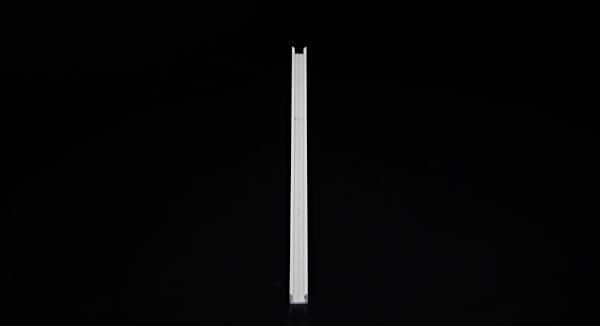 Ein schmales, vertikales Objekt steht im Fokus vor einem schwarzen Hintergrund.