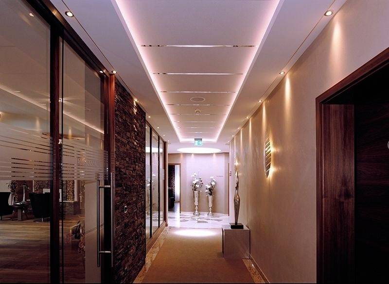 Ein eleganter, schmaler Flur mit weicher Beleuchtung und Dekorationen, führt zu einem Raum am Ende des Korridors.