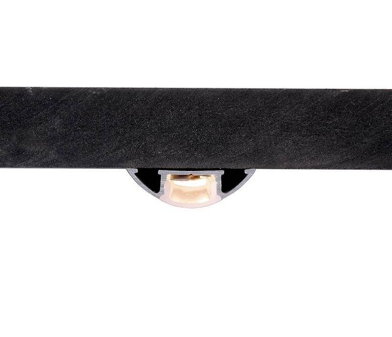 Ein schwarzer Balken mit einer runden Aussparung in der Mitte, die einen kleinen zylindrischen Gegenstand in der Farbe Beige zeigt.