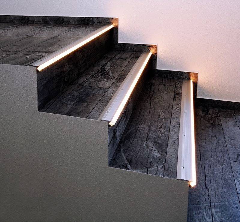 Eine Treppe mit dunklen Holzstufen und integrierten LED-Leuchten an den Kanten für erhöhte Sichtbarkeit und Sicherheit.
