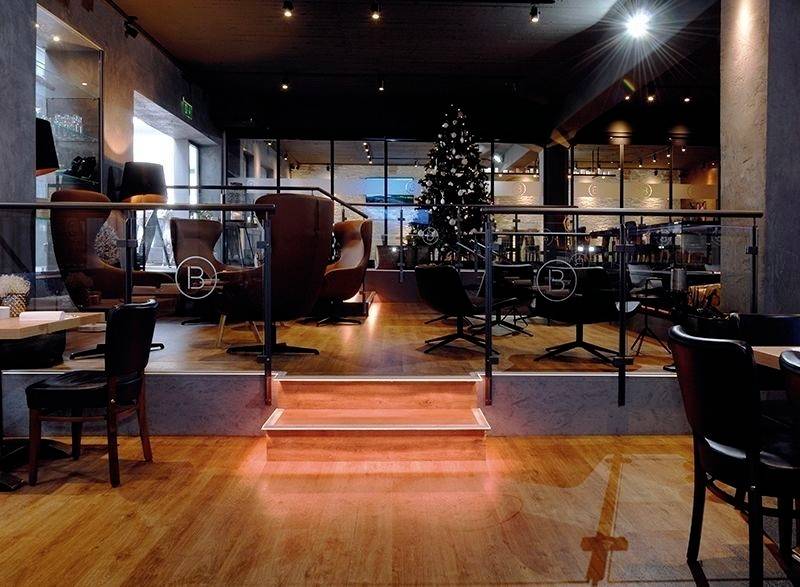 Ein stilvoll eingerichteter, moderner Café-Raum mit entspanntem Ambiente. Im Hintergrund steht ein geschmückter Weihnachtsbaum.