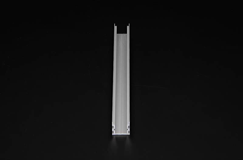 Ein langer, schmaler Metallkanal liegt flach auf einem dunklen Hintergrund und zeigt zur Kamera.