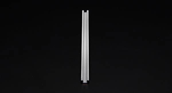 Eine einzelne silberne Schiene liegt vertikal in der Bildmitte auf schwarzem Hintergrund.