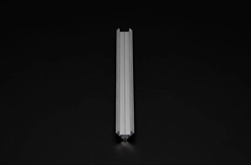 Eine graue, metallische, längliche Schiene liegt auf einem schwarzen Hintergrund. Sie ist symmetrisch mit zwei parallel verlaufenden Kanten.