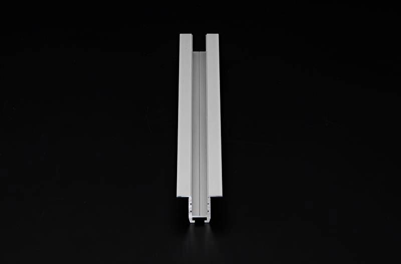 Ein silbernes Aluminiumprofil vor einem schwarzen Hintergrund. Das Profil ist länglich und hat eine symmetrische Nut in der Mitte.