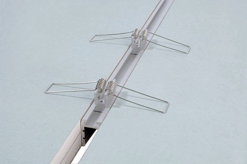 Eine Dehnfuge in einer abgehängten Decke mit Metallschlitten und Federn. Sie ermöglicht Bewegungsausgleich und Strukturstabilität.