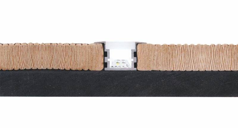 Querschnitt einer Dehnfuge in einem Bodenbelag. Zwischen zwei Holzplatten ist eine Dehnungsfuge mit einem Metalleinsatz sichtbar.