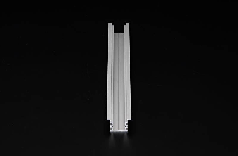 Ein graues Aluminiumprofil mit einer symmetrischen, kanalartigen Form in der Mitte, vor schwarzem Hintergrund.