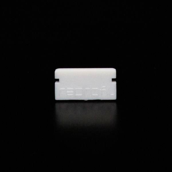 Weiße Rasierklinge vor schwarzem Hintergrund, mit unleserlichem Text eingeprägt.