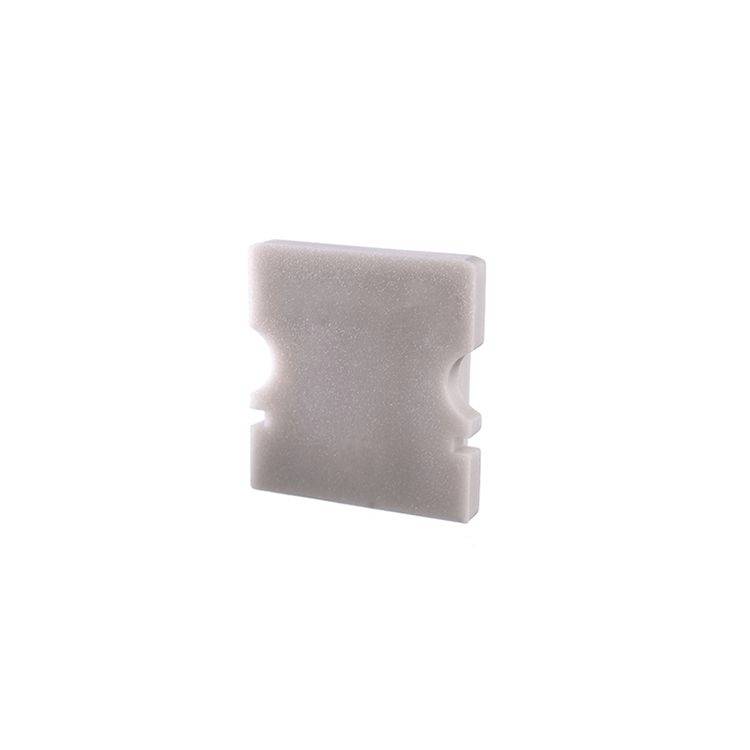 Graues Schaumstoffstück, quadratisch mit zwei seitlichen Einkerbungen.