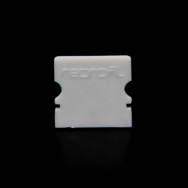 Weiße Kunststoffklinge mit der Aufschrift 'reprofil' auf schwarzem Hintergrund. Sie wirkt wie eine Schutzkappe für Rasierblätter.
