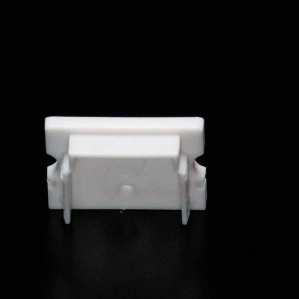 Ein kleines weißes Plastikobjekt mit Clips, Ansicht von oben, vor einem schwarzen Hintergrund.