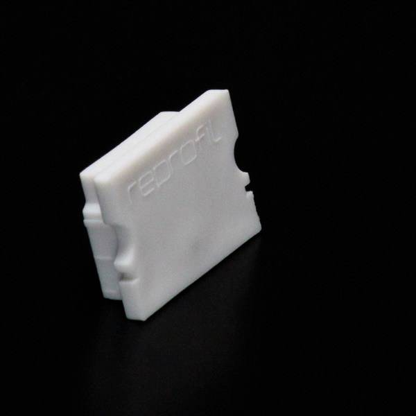 Ein weißer, rechteckiger Kunststoffbaustein mit der Aufschrift 'reprofil' auf schwarzem Hintergrund.