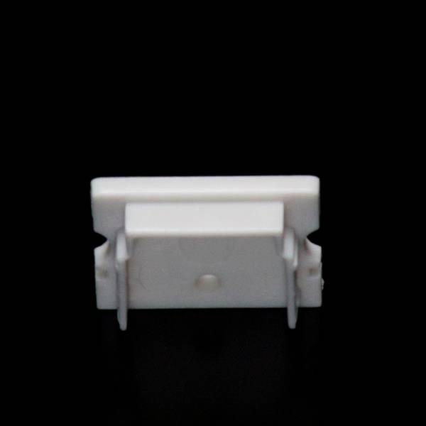 Ein weißer, rechteckiger Plastikclip auf schwarzem Hintergrund; dient möglicherweise zur Befestigung oder Organisation von Kabeln.