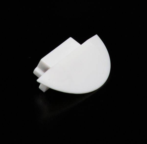Ein weißes, halbkreisförmiges Kunststoffteil vor schwarzem Hintergrund.