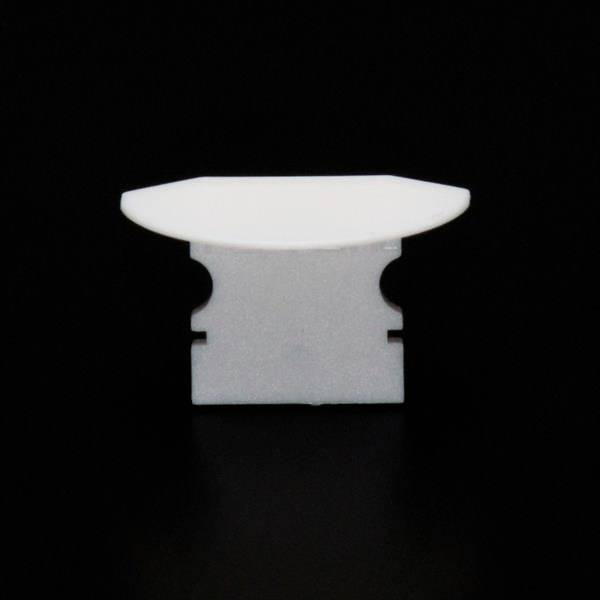 Ein weißes, ovales Objekt auf einem schwarzen Hintergrund, welches an ein minimalistisches Möbelstück erinnert.