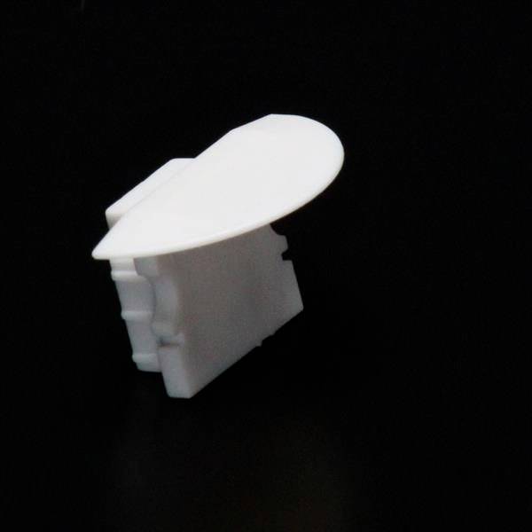 Ein weißer, rechteckiger Kunststoffverschluss mit einem runden Griff liegt auf schwarzem Hintergrund.