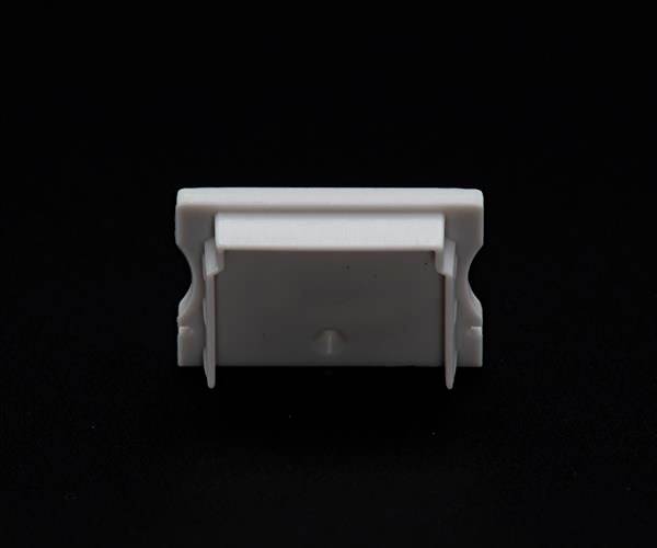 Weiße, rechteckige Kunststoffklammer vor schwarzem Hintergrund.