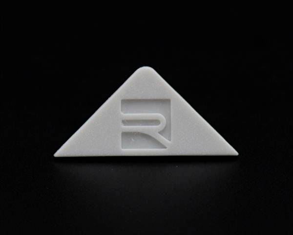 Graues, dreieckiges Objekt mit einem stilisierten 'R' in der Mitte auf schwarzem Hintergrund.