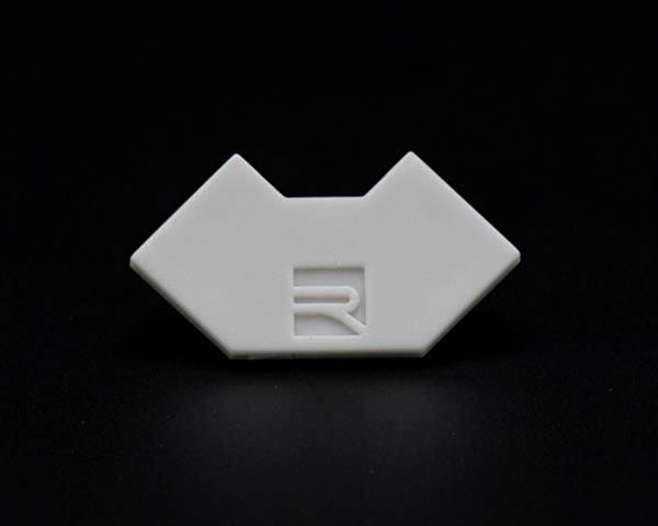 Eine weiße, geometrische Form mit einem eingravierten Logo in der Mitte, vor einem schwarzen Hintergrund.