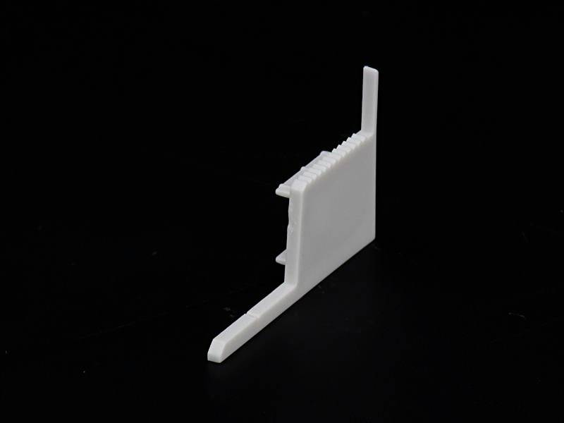 Ein weißer, keilförmiger Kunststoffgegenstand vor schwarzem Hintergrund.